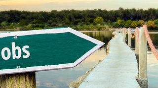 Sign saying "Jobs" in front of a bridge with a lake